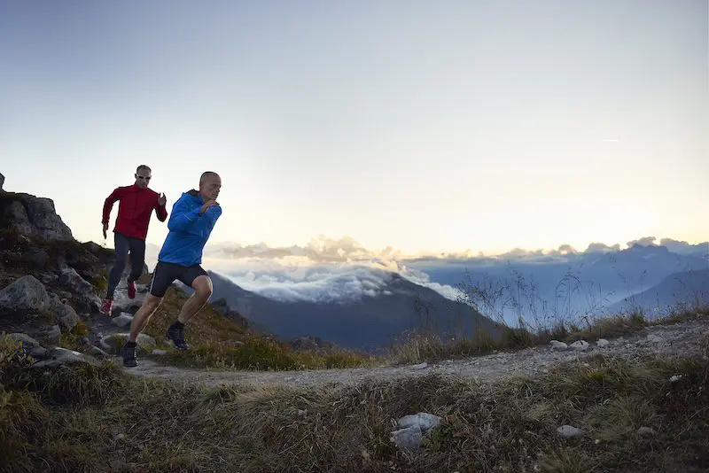Mannen lopen op pad in de bergen - trailrunning