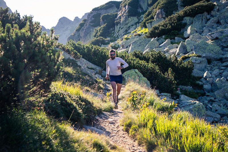 Trailrunner loopt op pad tussen de rotsen